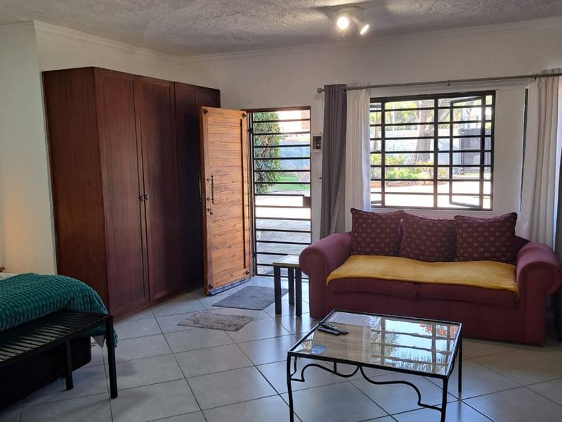Open plan living area featuring tiled flooring, a built-in wardrobe, and direct access to the exterior via a security gate.