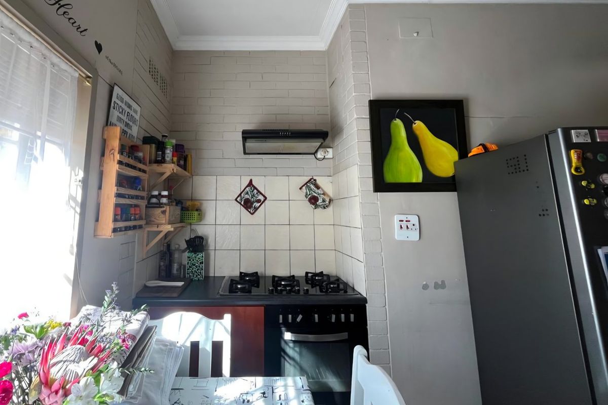 Compact kitchen area featuring a built-in gas hob, oven, extractor fan, and tiled backsplash with a neutral brick-style wall finish.