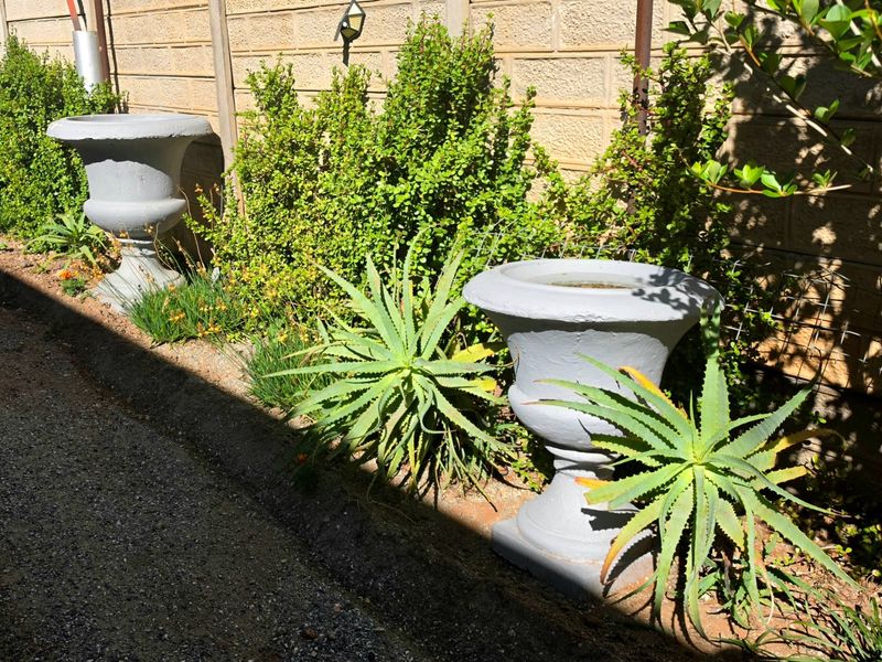 A landscaped garden area featuring a brick boundary wall with an integrated exterior light fixture and decorative stone planters.