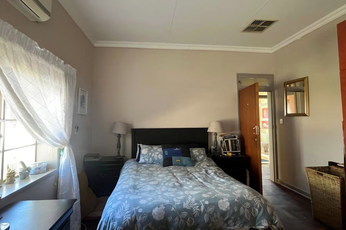 A functional bedroom featuring a split-system air conditioner, ceiling ventilation, and coved cornicing, providing a comfortable and well-maintained living space.