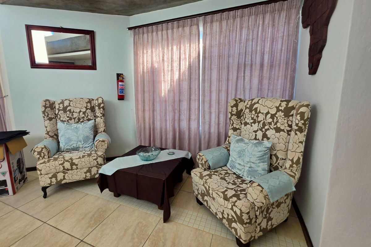 A cozy living area featuring tiled flooring, recessed ceiling lighting, and a wall-mounted fire extinguisher, providing a functional and well-lit space.