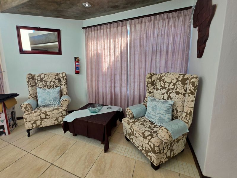 A cozy living area featuring tiled flooring, recessed ceiling lighting, and a wall-mounted fire extinguisher, providing a functional and well-lit space.