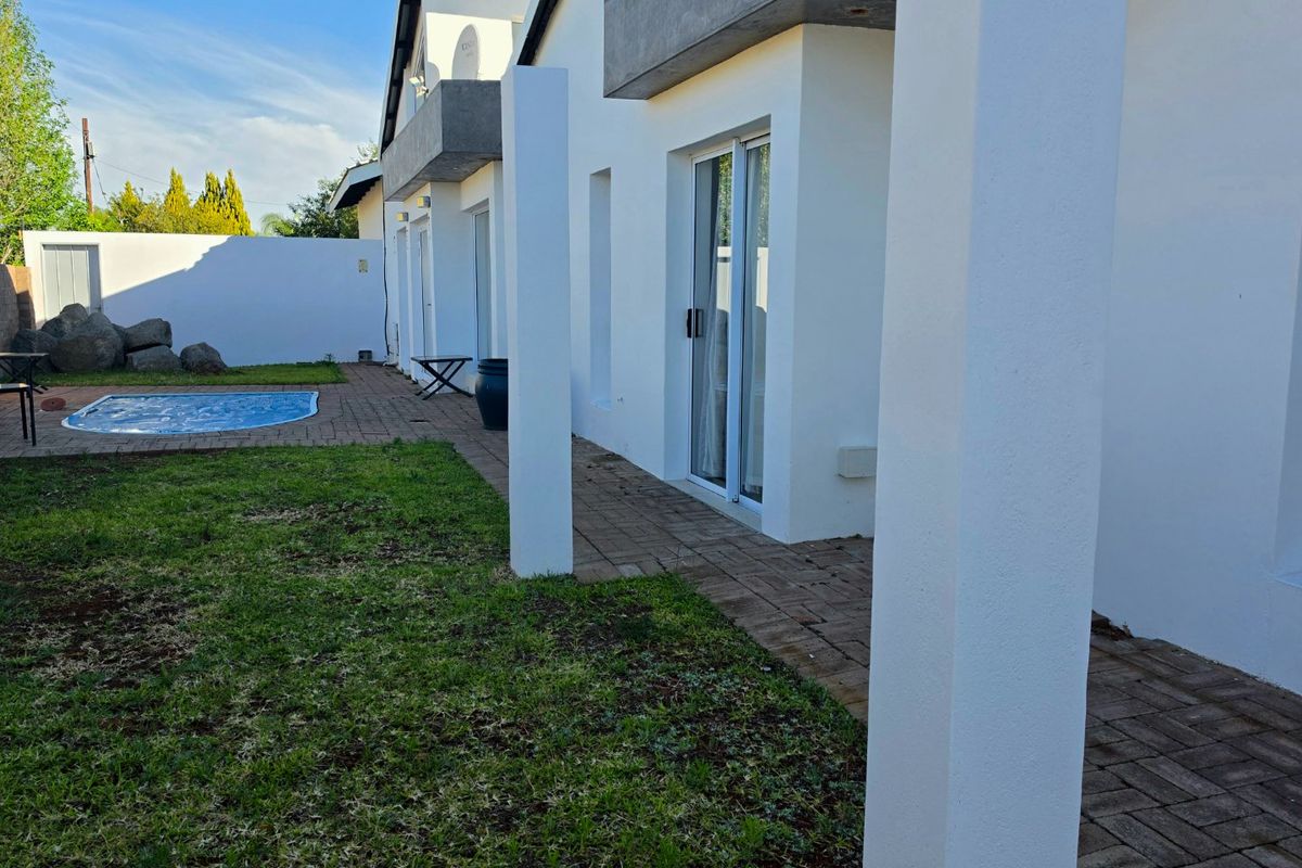 Rear exterior view featuring a paved patio area, swimming pool, and access to the home via sliding glass doors.
