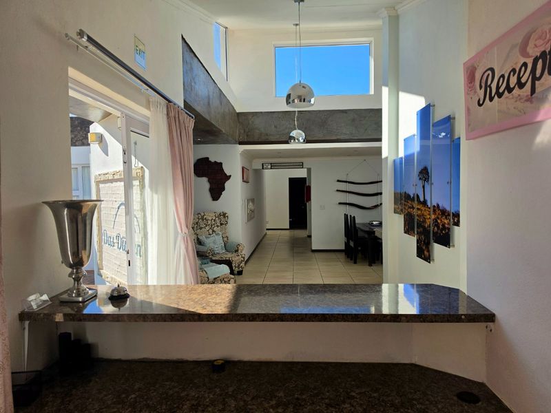 A bright entrance area featuring a built-in reception counter, double volume ceilings with pendant lighting, and tiled flooring leading into the main living space.