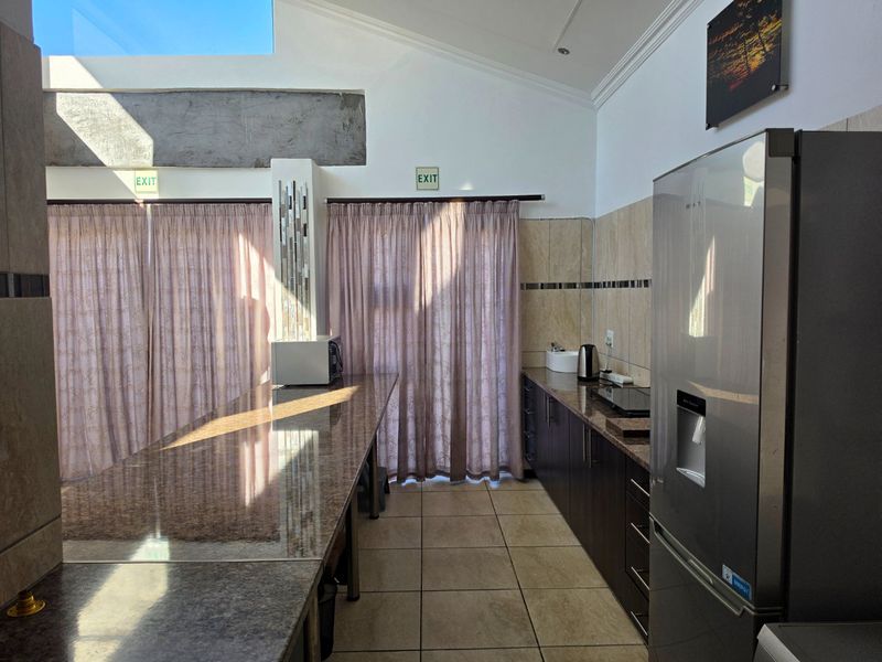 A functional kitchen featuring granite countertops, dark cabinetry, tiled flooring, and a skylight, providing a bright and practical workspace.