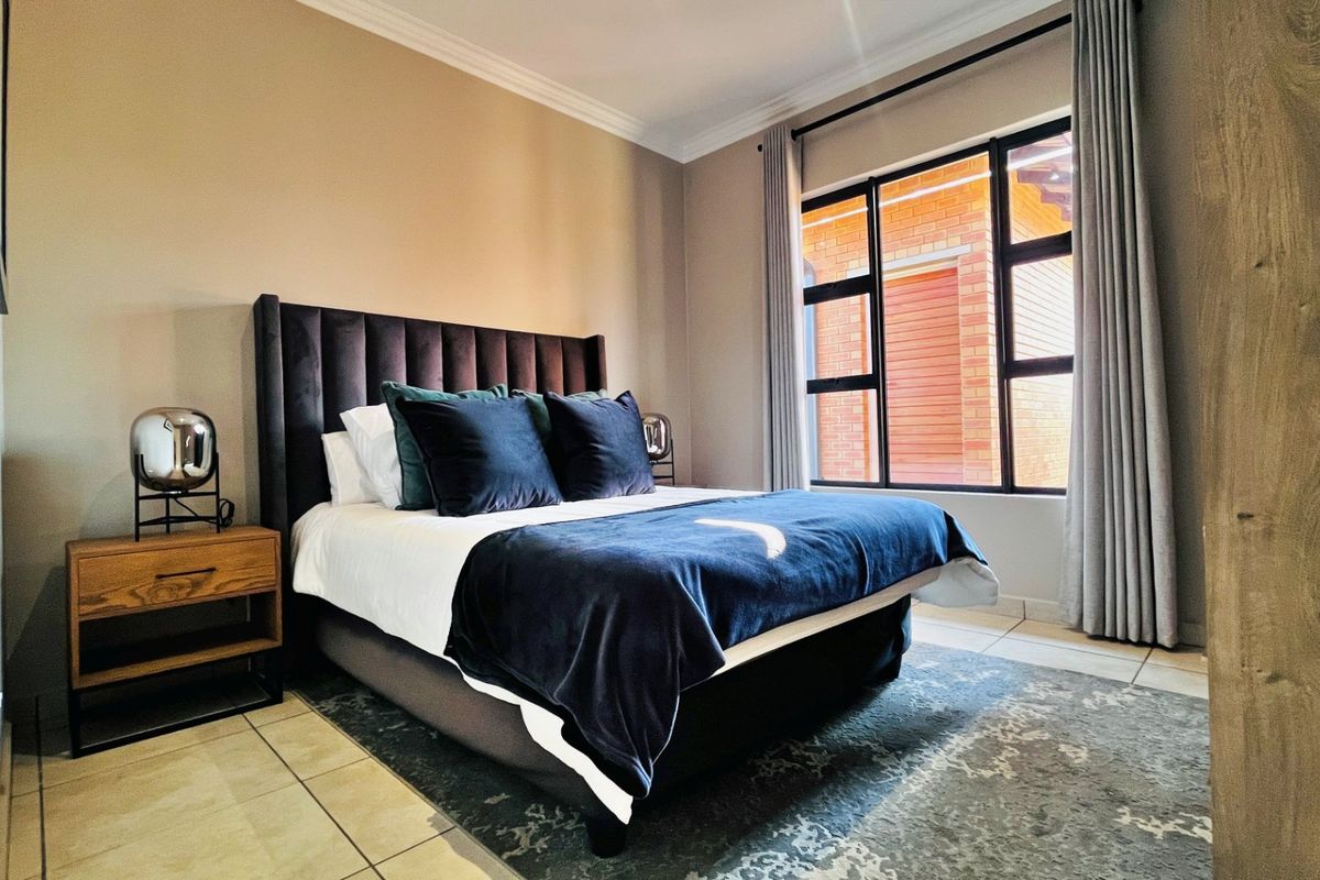 A well-maintained bedroom featuring tiled flooring, modern aluminium window frames, and elegant cornicing, providing a comfortable and inviting living space.