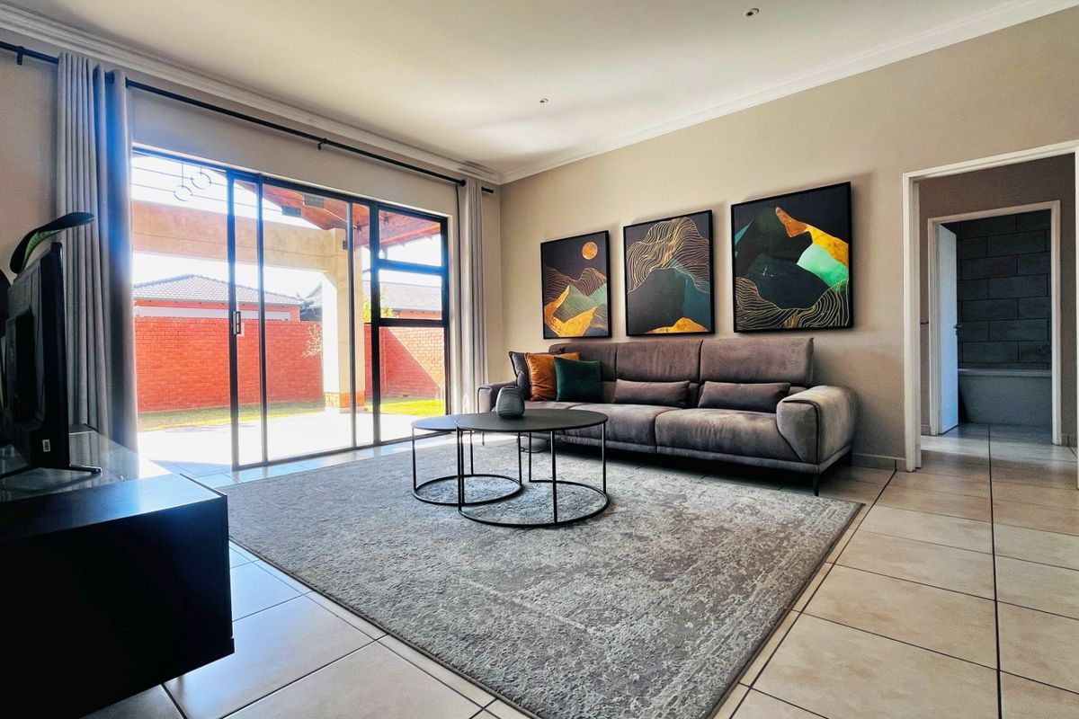 A well-maintained living room featuring tiled flooring, recessed lighting, and large sliding glass doors that provide direct access to the outdoor patio area.