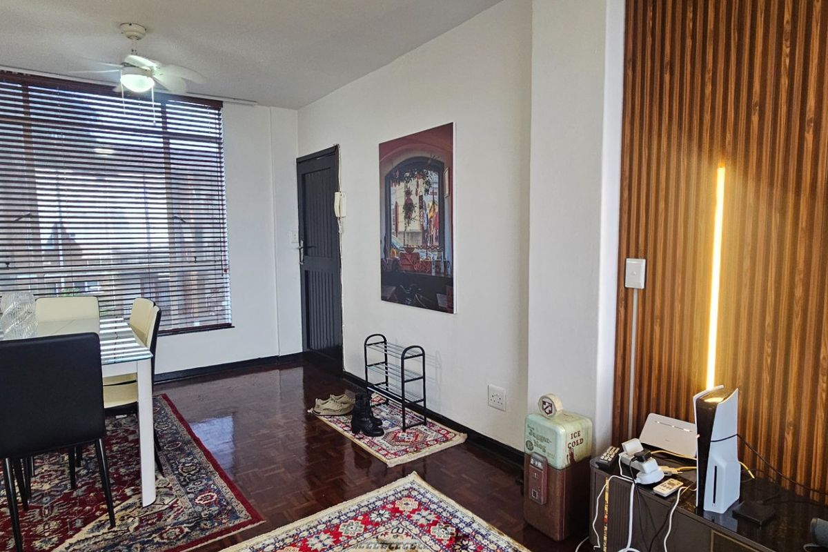 Living area featuring polished parquet flooring, a decorative timber slat feature wall, and a ceiling fan, with large windows fitted with venetian blinds.