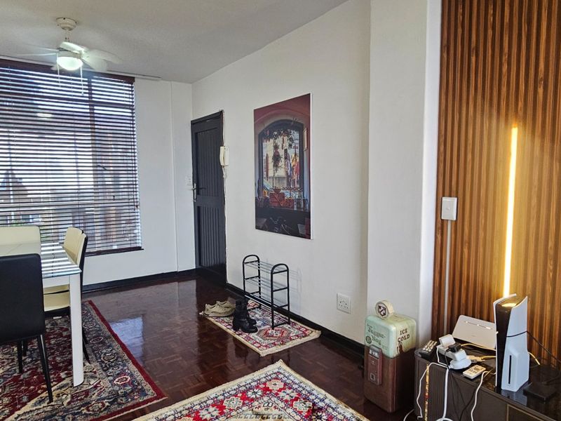 Living area featuring polished parquet flooring, a decorative timber slat feature wall, and a ceiling fan, with large windows fitted with venetian blinds.