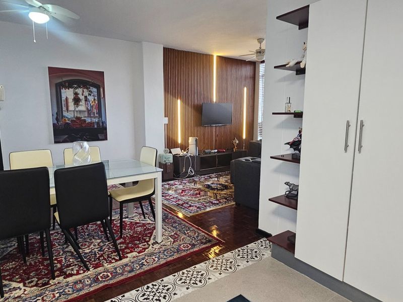 Open plan living and dining area featuring a modern slatted wood accent wall with integrated lighting and a built-in storage unit.