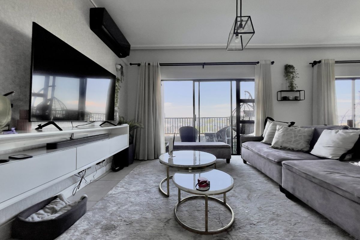 A bright and modern living room featuring tiled floors, a wall-mounted air conditioning unit, and large sliding glass doors leading to a balcony.