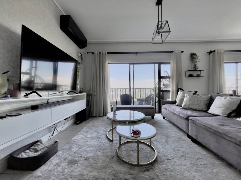 A bright and modern living room featuring tiled floors, a wall-mounted air conditioning unit, and large sliding glass doors leading to a balcony.