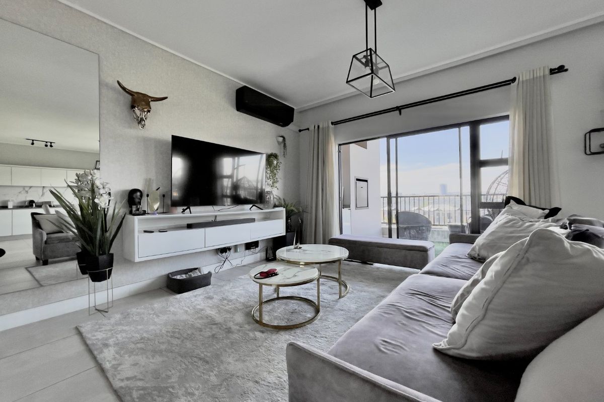 Modern living room featuring a wall-mounted media console, split-system air conditioning, and large sliding glass doors leading to a balcony with natural light.