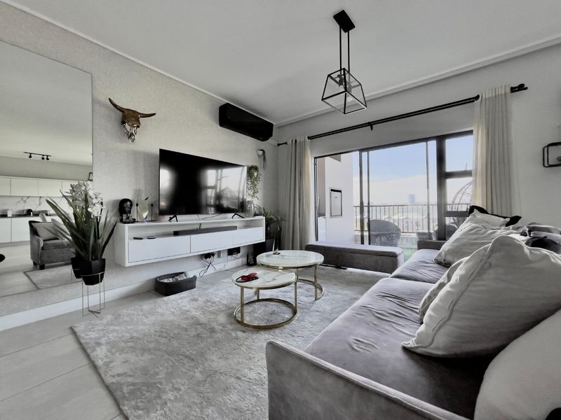 Modern living room featuring a wall-mounted media console, split-system air conditioning, and large sliding glass doors leading to a balcony with natural light.