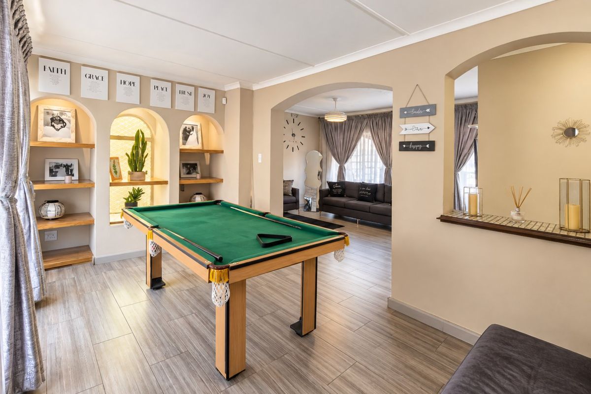 Spacious living area featuring built-in arched shelving, tiled flooring, and an open-plan layout connecting to an adjacent lounge space.