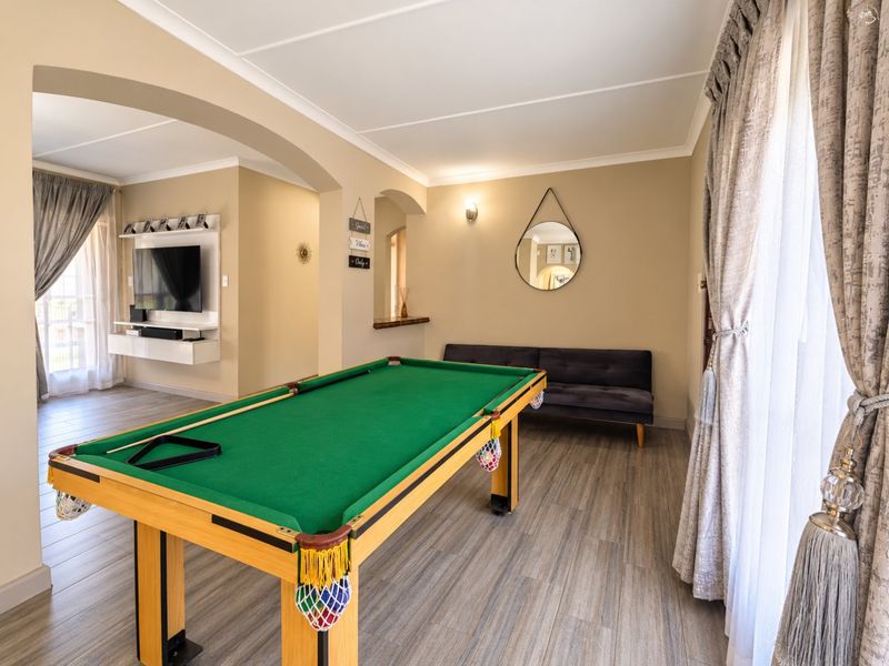 Spacious living area featuring wood-look laminate flooring, an elegant archway, and a built-in media console, currently utilized as a games room.