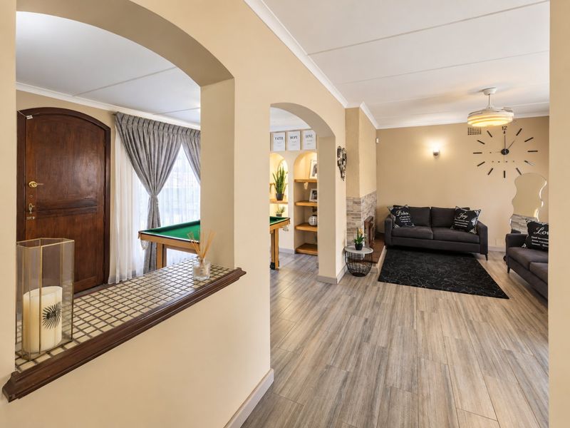 Spacious living area featuring laminate flooring, arched transitions, a stone-clad fireplace, and built-in shelving, creating a warm and inviting open-plan atmosphere.