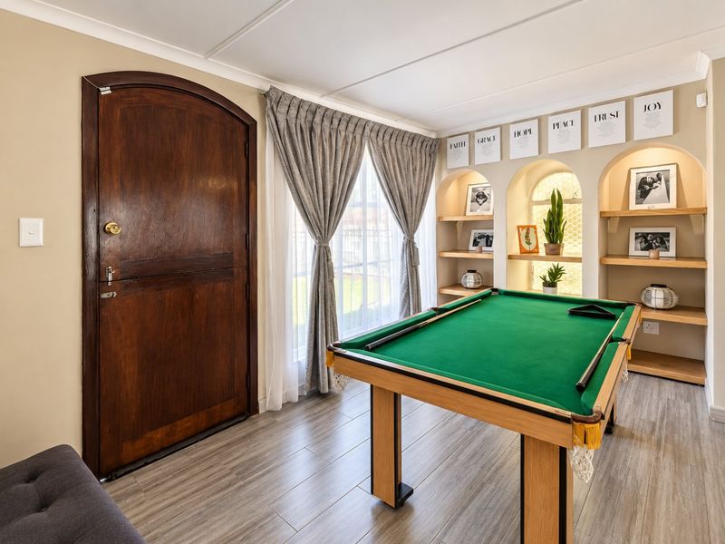A well-maintained living area featuring arched wall niches with built-in shelving, a classic timber arched door, and modern laminate flooring.