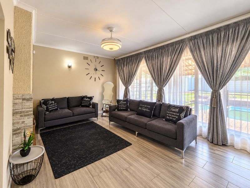 A bright and well-maintained living room featuring tiled flooring, a stone-clad fireplace, and large sliding glass doors providing access to the outdoor area.
