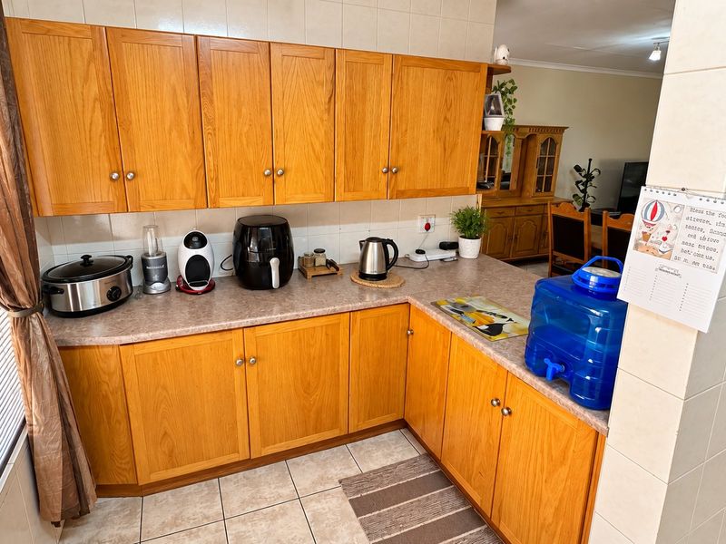 A functional kitchen featuring wood-look laminate cabinetry, ample countertop workspace, and tiled flooring, offering a practical layout for daily meal preparation.