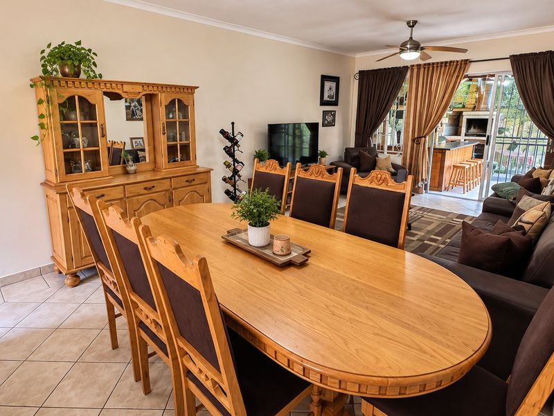 Open-plan living and dining area featuring tiled flooring, a ceiling fan, and seamless access to an outdoor patio with a built-in braai.