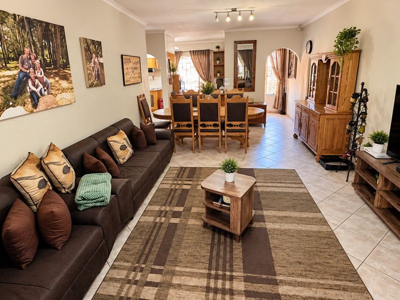 Spacious open-plan living and dining area featuring ceramic floor tiles, an arched transition to the kitchen, and neutral wall finishes.