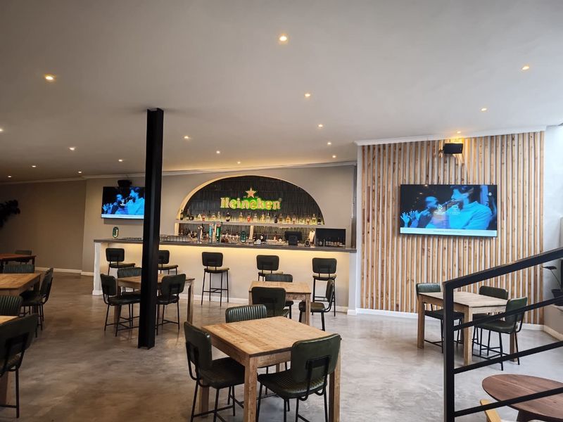 A modern bar area featuring a built-in counter, timber slat wall accents, polished concrete floors, and recessed ceiling lighting.