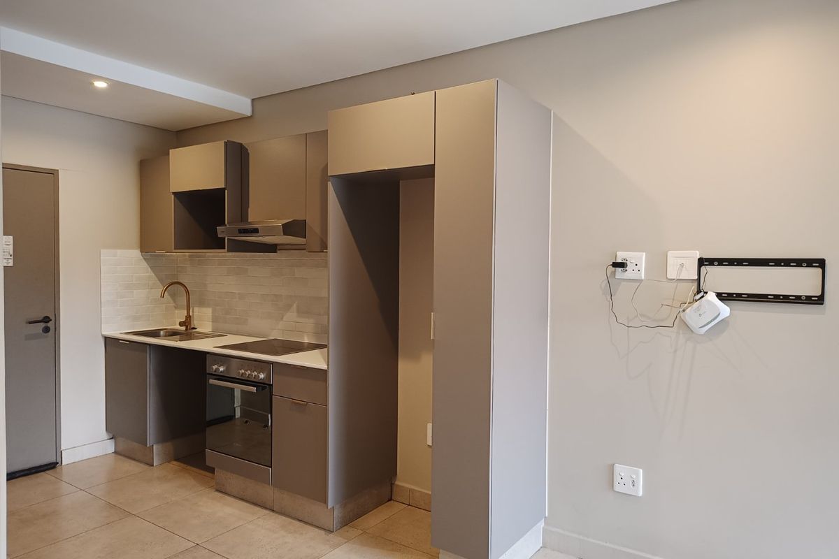 Modern compact kitchen featuring neutral cabinetry, integrated appliances, subway tile backsplash, and tiled flooring in an open-plan layout.
