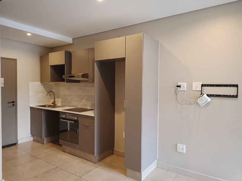Modern compact kitchen featuring neutral cabinetry, integrated appliances, subway tile backsplash, and tiled flooring in an open-plan layout.