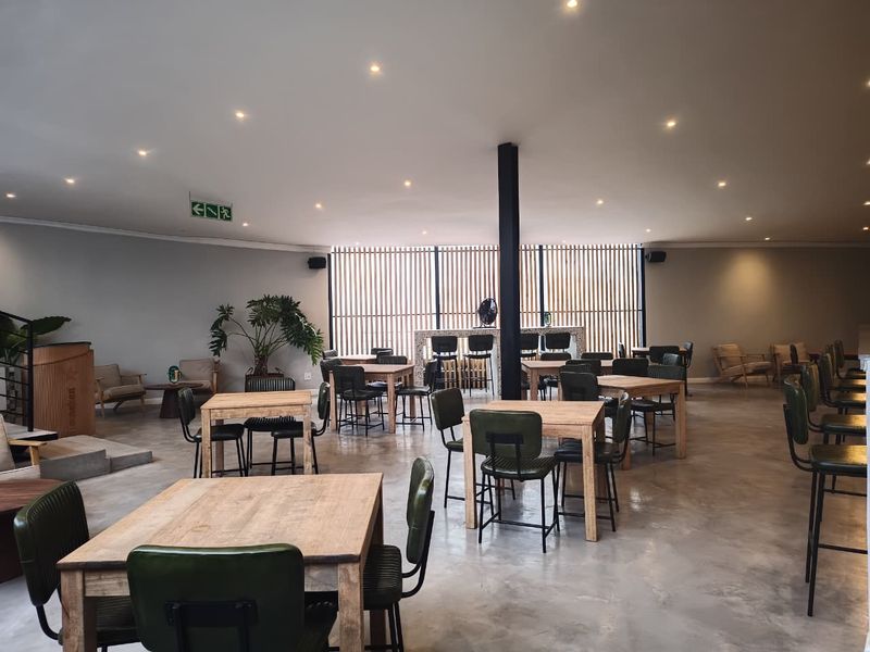 Spacious clubhouse area featuring polished concrete floors, recessed lighting, a central structural column, and a decorative slatted timber screen wall with a built-in bar.
