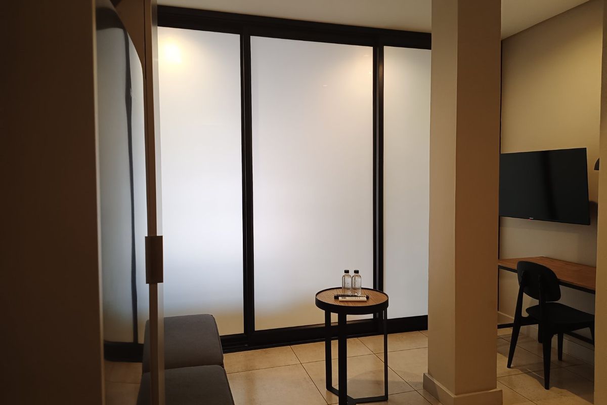 Modern bedroom featuring tiled flooring, a structural column, and large frosted glass sliding doors that provide a clean, contemporary aesthetic.