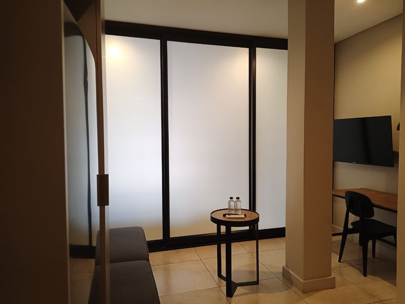 Modern bedroom featuring tiled flooring, a structural column, and large frosted glass sliding doors that provide a clean, contemporary aesthetic.