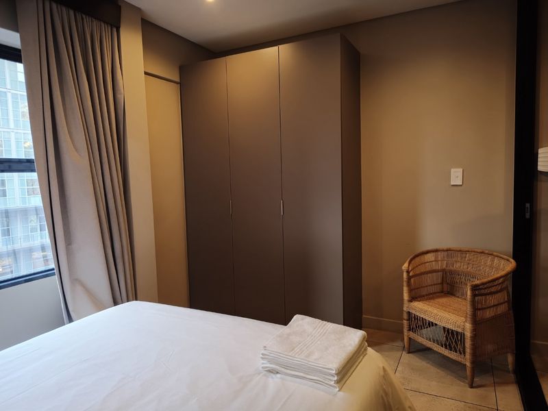 A well-maintained bedroom featuring neutral walls, tiled flooring, recessed lighting, and a large built-in wardrobe for ample storage.