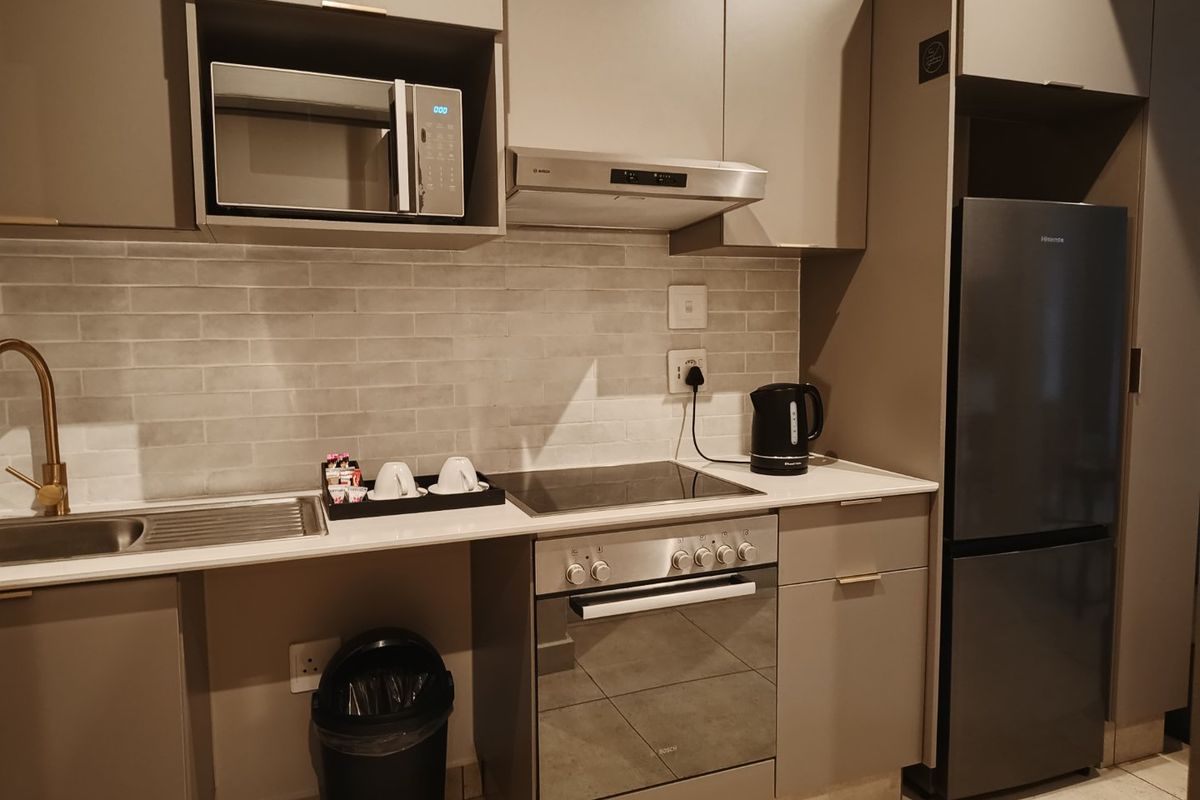 Modern kitchen featuring sleek cabinetry, subway tile backsplash, integrated stainless steel appliances, and a stone countertop with a brass faucet.