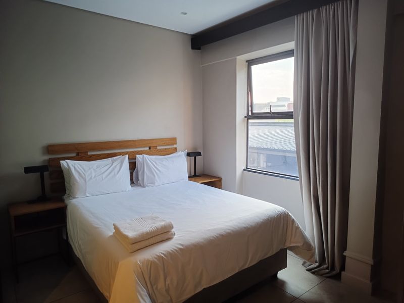 A well-maintained bedroom featuring tiled flooring, recessed ceiling lighting, and a window with neutral curtains.