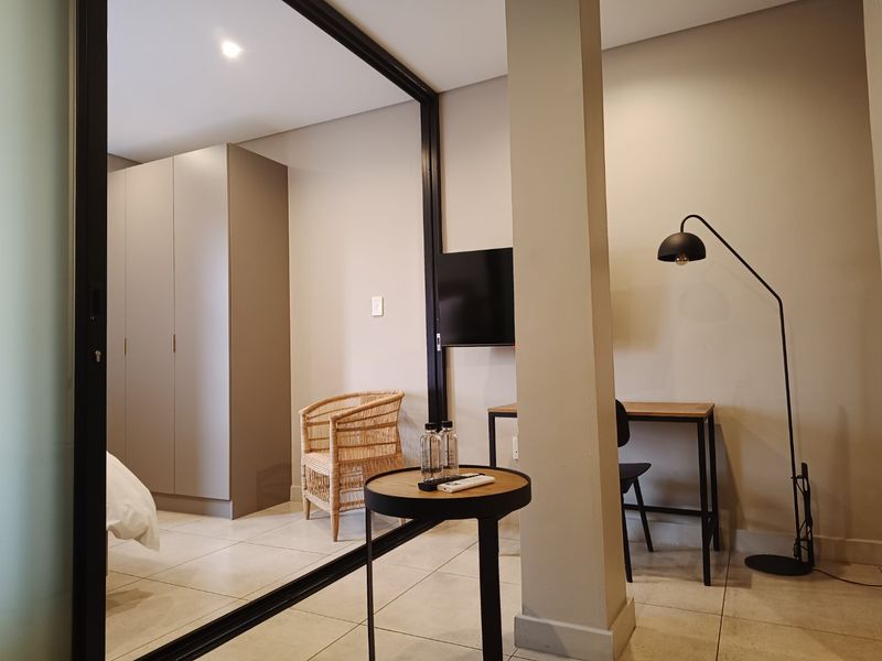 A modern bedroom featuring tiled flooring, a built-in wardrobe, and a sleek sliding glass partition, creating a clean and contemporary living space.