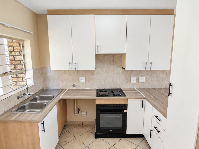 A functional kitchen featuring white cabinetry, laminate countertops, a built-in oven and hob, and a double basin sink with tiled backsplash.