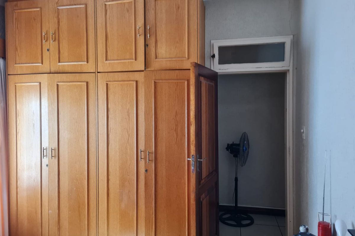 Bedroom featuring extensive built-in wooden cabinetry and tiled flooring, with a doorway leading to an adjacent space.