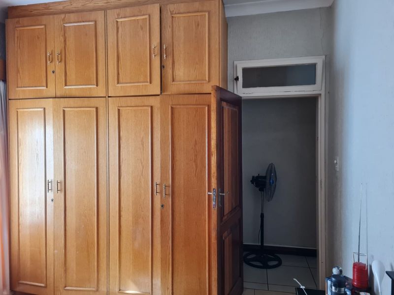 Bedroom featuring extensive built-in wooden cabinetry and tiled flooring, with a doorway leading to an adjacent space.