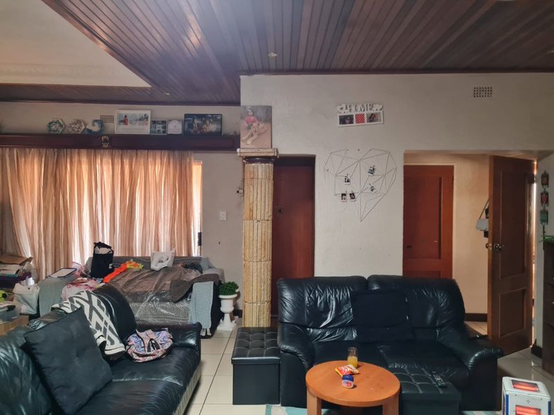 A living room featuring a timber tongue and groove ceiling, tiled flooring, and a decorative stone pillar, providing a traditional layout.