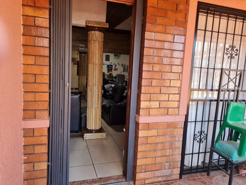 Entrance area featuring a brick facade, security gate, and a decorative column leading into the interior living space.