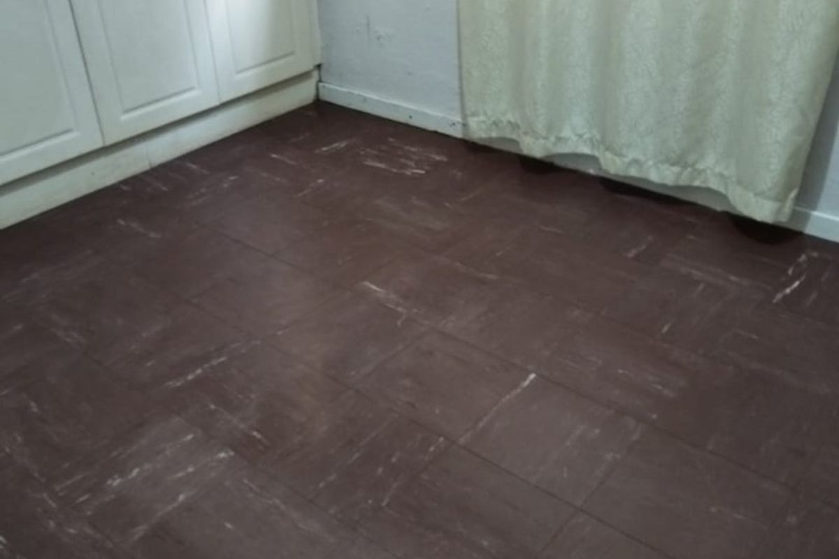 An empty bedroom featuring built-in cupboards and dark vinyl tile flooring, presenting a blank canvas for potential renovation and interior updates.