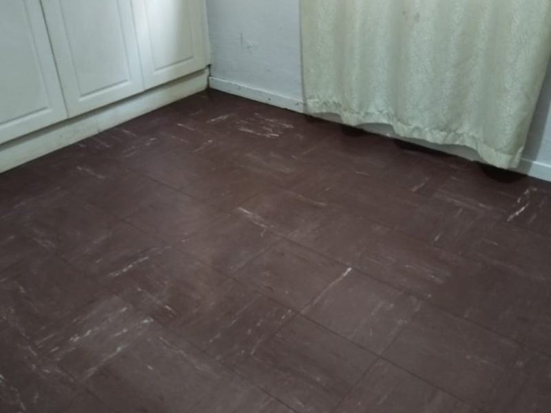 An empty bedroom featuring built-in cupboards and dark vinyl tile flooring, presenting a blank canvas for potential renovation and interior updates.