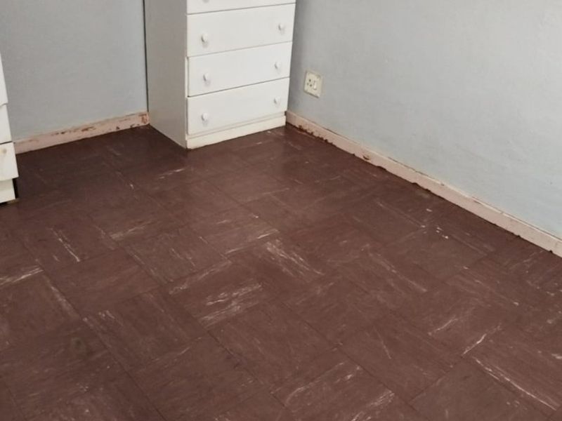 A bedroom featuring dark vinyl tile flooring and visible wall-to-floor transitions requiring baseboard installation or repair.