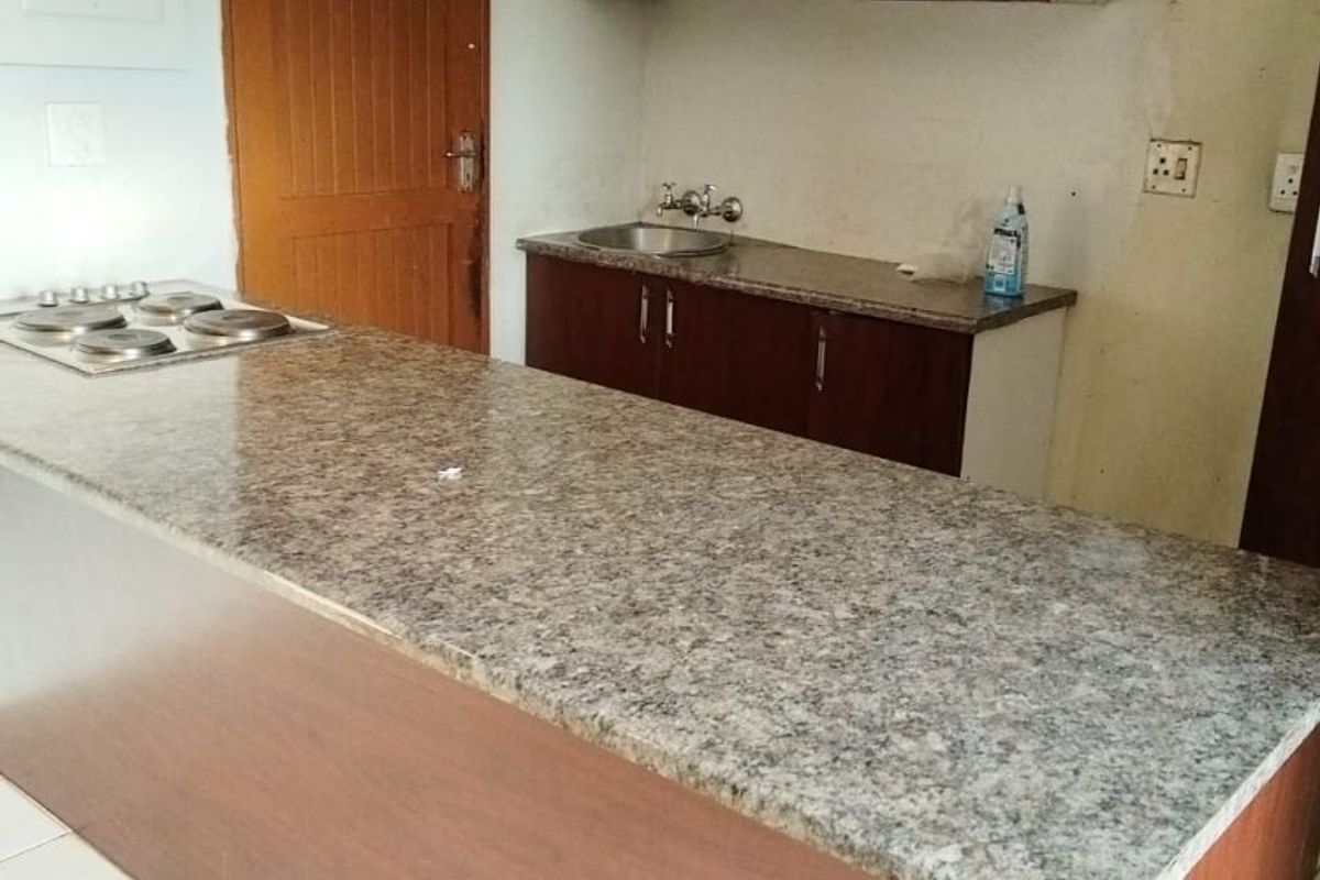 A functional kitchen area featuring a granite breakfast bar, built-in cabinetry, and an integrated electric hob, requiring minor cosmetic finishing to complete the space.