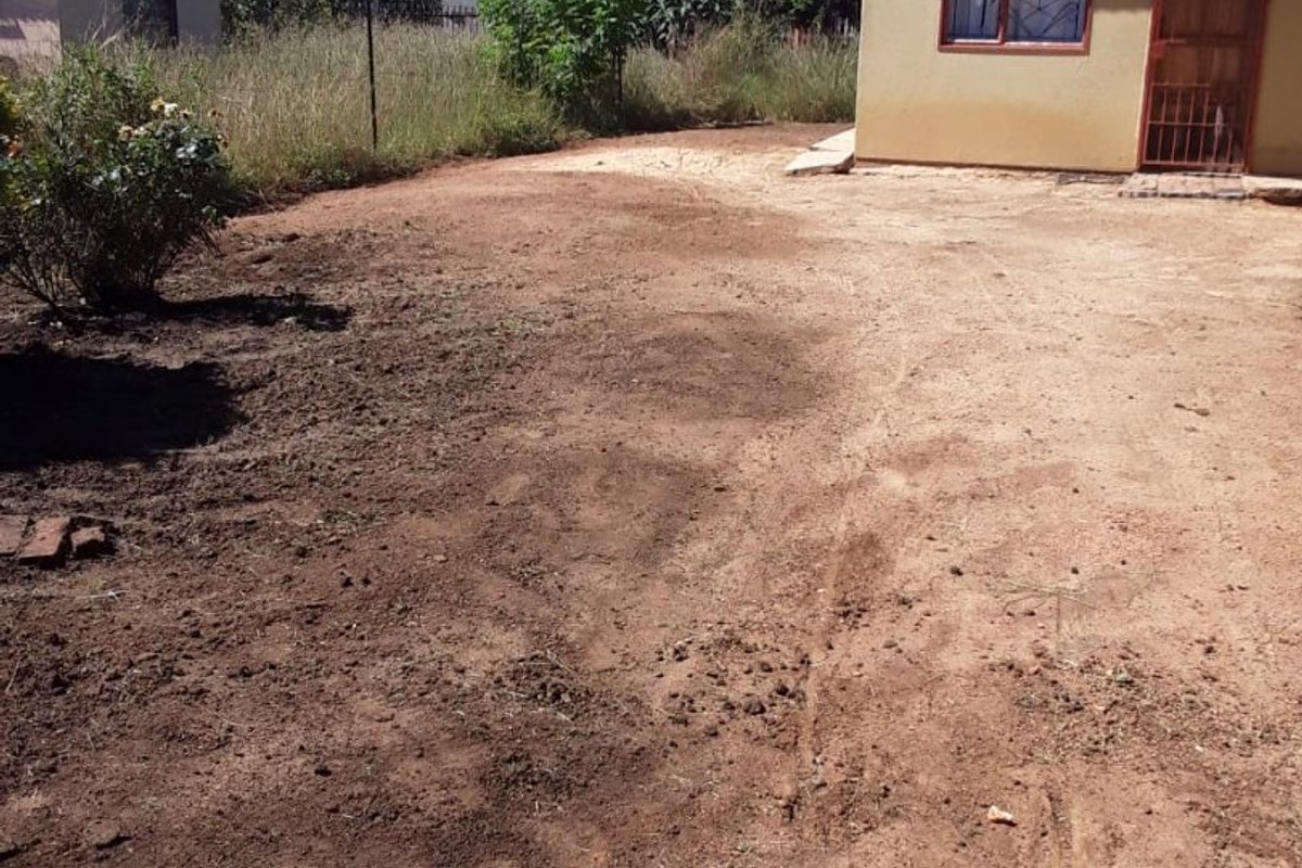 A view of the rear exterior of the house featuring a tiled roof and an unlandscaped yard with exposed soil.