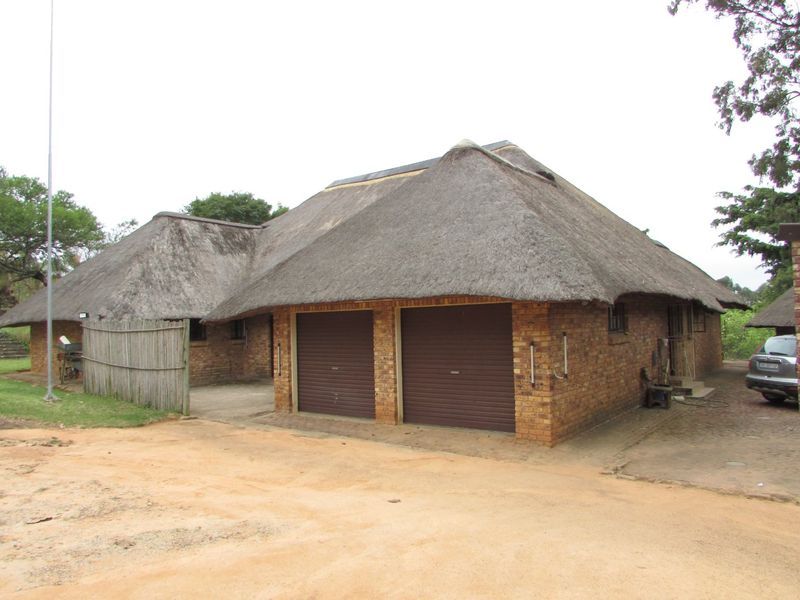 Front exterior view of a traditional farm-style residence featuring a thatched roof, face brick construction, and an integrated double garage.