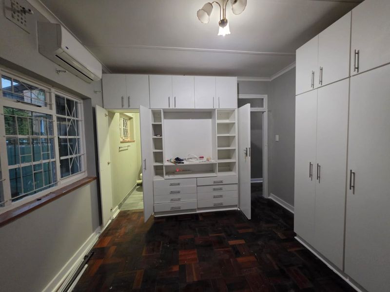 Bedroom featuring extensive built-in cabinetry, parquet flooring, and an integrated air conditioning unit, offering ample storage space.