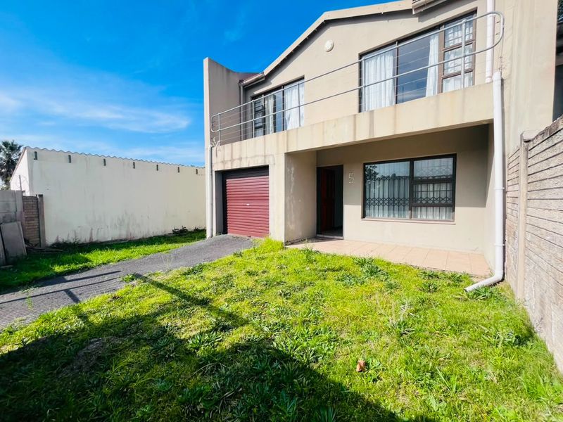 Front exterior view of a two-story house featuring a garage, balcony with metal railing, and a small front garden area.