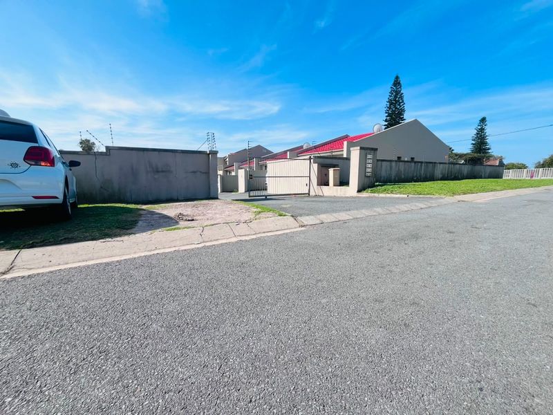 Front exterior view of the property featuring a perimeter wall with electric fencing, a gated entrance, and a red metal roof.